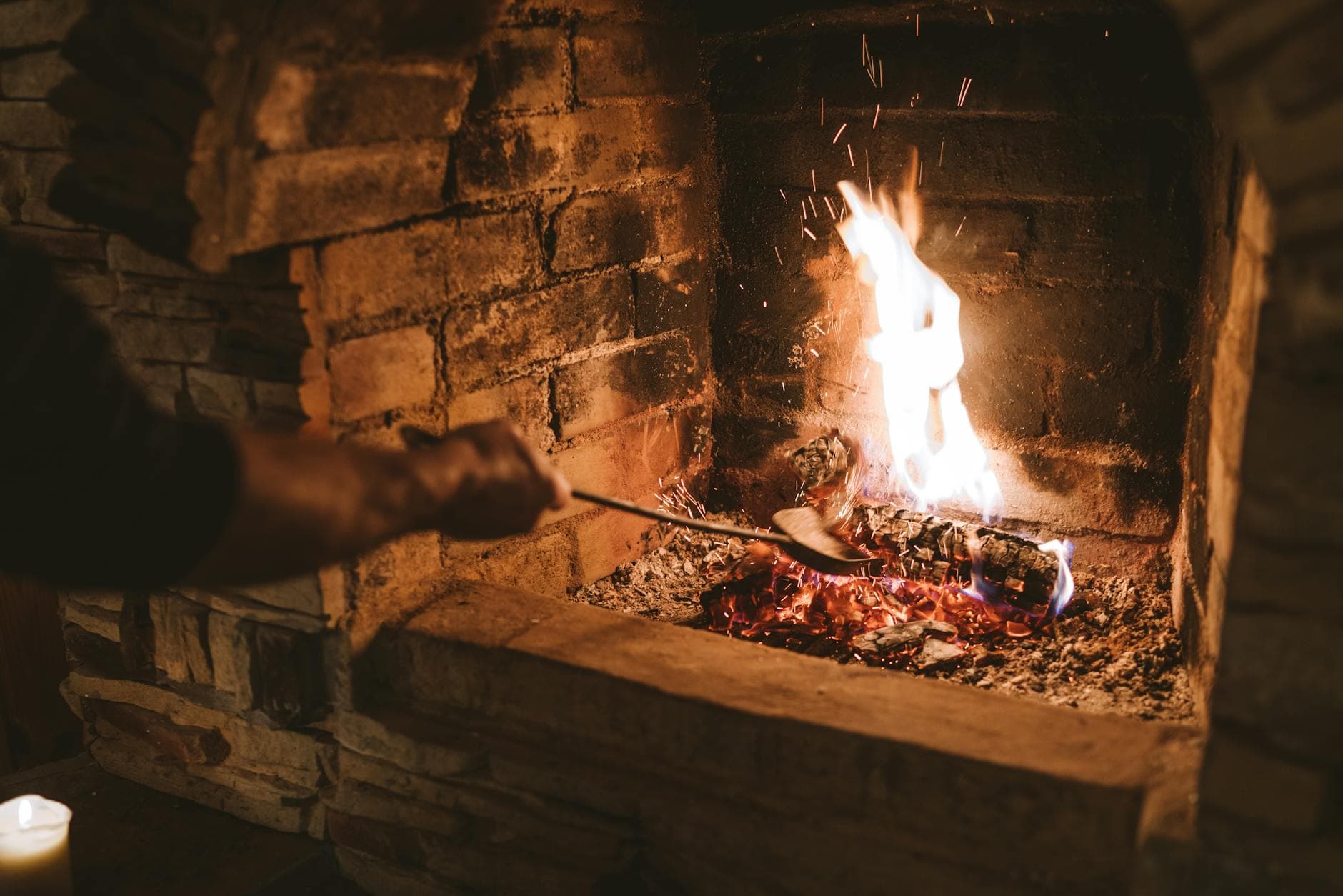 A warm and inviting fireplace with flames dancing on logs in a brick surround, perfect for winter comfort.